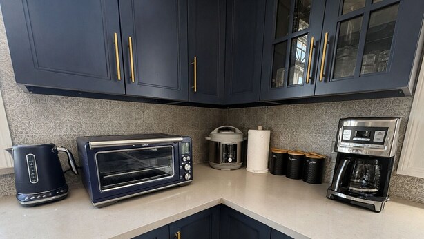 A kitchen with dark cabinets, a toaster oven, a coffee maker, and a kettle.