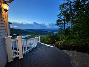A wooden deck with a white railing overlooking a scenic landscape.