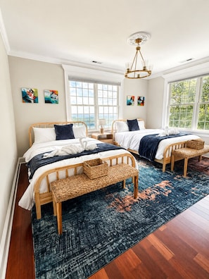 A bedroom with two beds, a large window, and a chandelier.