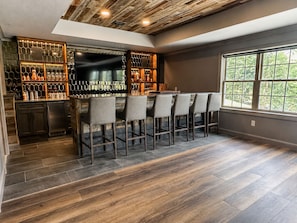 Un espace bar avec un plafond en bois, une grande fenêtre et un comptoir avec des tabourets.