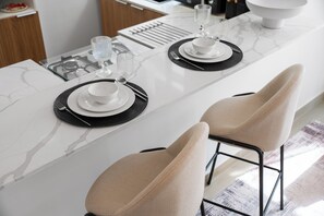 Uma cozinha moderna com bancada de mármore, dois banquetes e um conjunto de mesa e cadeiras.