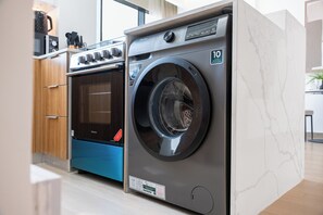A modern laundry room with a front-loading washing machine, a dryer, and a built-in oven. - StayShort - Amazing 1 Bedroom in JVC that Sleeps 4! (JVC)