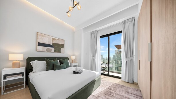 Una camera da letto moderna con un letto grande, lampade sui comodini, vista sulla città dalla finestra e panorama urbano dal balcone.