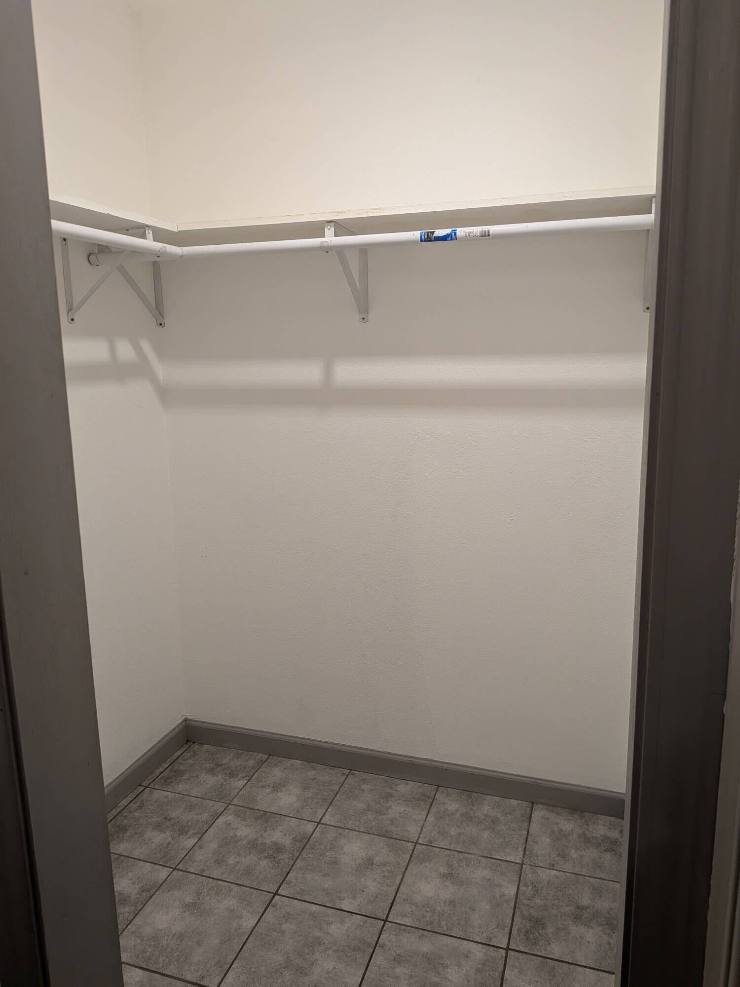 Vestidor con piso de baldosas y paredes blancas.