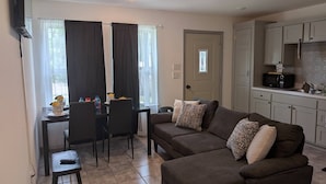 A compact living space with a kitchenette, a dining area with a table and chairs, and a sofa with patterned cushions. - Herrling Home (Dallas)