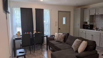 A compact living space with a kitchenette, a dining area with a table and chairs, and a sofa with patterned cushions.