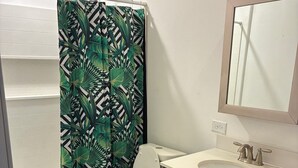 A bathroom with a toilet, sink, and shower curtain. - Herrling Home (Dallas)