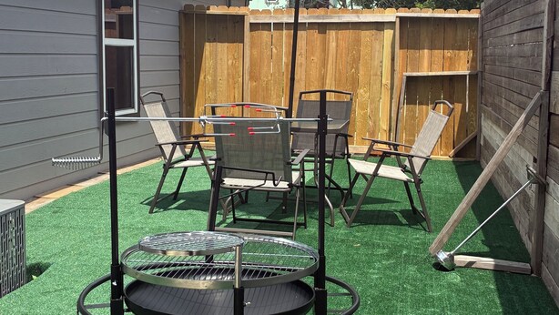A backyard with artificial turf, a round table, and outdoor furniture. - Herrling Home (Dallas)