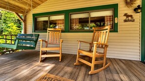 A porch with two rocking chairs and a bench, a welcome mat, and a 'Welcome' sign with a moose decoration.