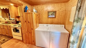 Un interno in legno con angolo cottura, dotato di piano cottura, forno e lavatrice.