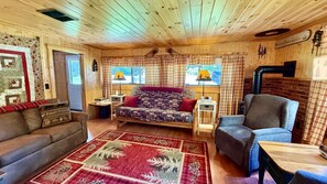 A cozy cabin interior with a sofa, armchair, and a rug. - Pet Friendly waterfront cabin just minutes from downtown Greenville (Greenville)