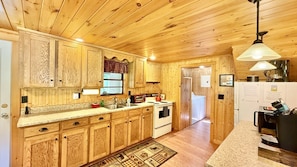 A wooden-paneled kitchen with a stove, sink, and cabinets.