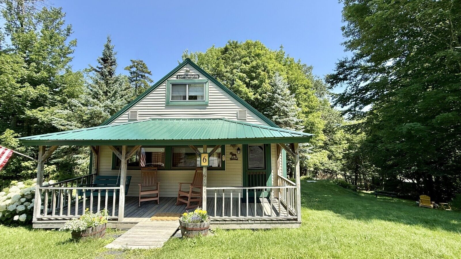 A two-story house with a porch, a small deck, and a front yard.