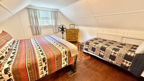 A dormitory room with two beds, a wooden dresser, a standing fan, and a window with curtains. - Pet Friendly waterfront cabin just minutes from downtown Greenville (Greenville)