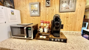 A kitchen with a microwave, coffee maker, and a note advising against feeding geese or ducks.