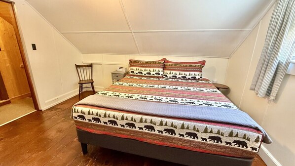 A bedroom with a bed, a chair, and a nightstand.