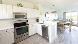 Una cocina moderna con armarios blancos, electrodomésticos de acero inoxidable y una mesa de comedor de madera.