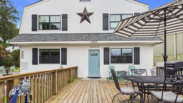 Un edificio de dos pisos con una puerta azul, una decoración de estrella sobre la entrada y una terraza con una mesa y sillas.