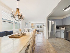 A modern kitchen with a dining area, stainless steel appliances, and a chandelier.