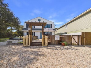 A short-term rental property with a gravel driveway, wooden gate, and a fenced yard.