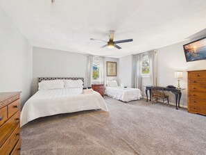 A bedroom with a large bed, a smaller bed, a desk, and a chair.