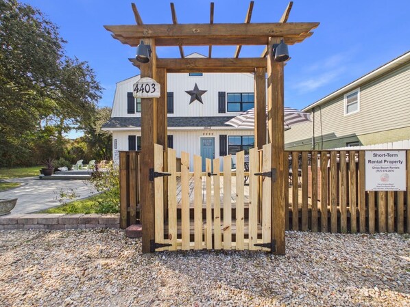 A gated entrance with a wooden gate and a sign indicating a short-term rental property.
