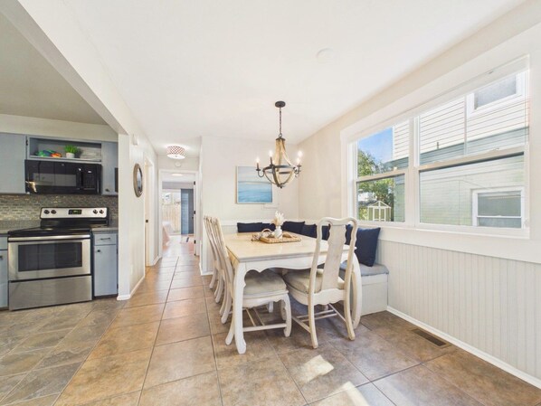 A kitchen with a dining area, a chandelier, and a window with a view.