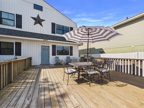 A wooden deck with a table and chairs, a star decoration on the building, and a blue door.