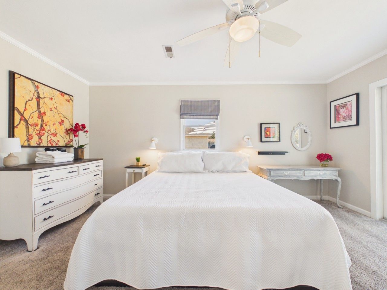 A bedroom with a bed, dresser, bedside tables, and a ceiling fan.
