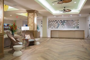 A lobby with a herringbone wood floor, wicker furniture, a reception desk, and a wall of circular mirrors. - Poolside Relaxation and Private Kitchen Amenities for the Perfect Stay! (Duck Key)