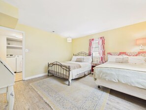 A bedroom with two beds, a wardrobe, a bedside table, and a lamp. - `The Greyson` - The Cottage Collection (Virginia Beach)