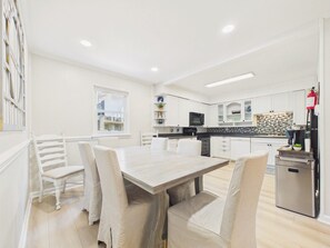 Uma cozinha moderna com armários brancos, uma mesa de jantar de madeira e um forno embutido.
