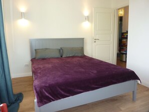 Ein Bett mit einer violetten Decke, einem hellblauen Kopfteil und zwei Wandleuchten.