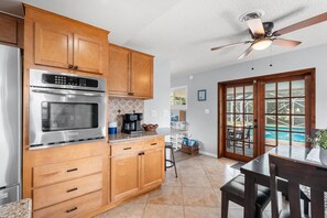 A kitchen with wooden cabinets, stainless steel appliances, and a ceiling fan. - Family‑Friendly Tropical Beach Home w/ Private Pool ☀️ (Indian Harbour Beach)
