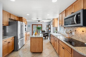 A modern kitchen with stainless steel appliances, wooden cabinets, and a central island. - Family‑Friendly Tropical Beach Home w/ Private Pool ☀️ (Indian Harbour Beach)