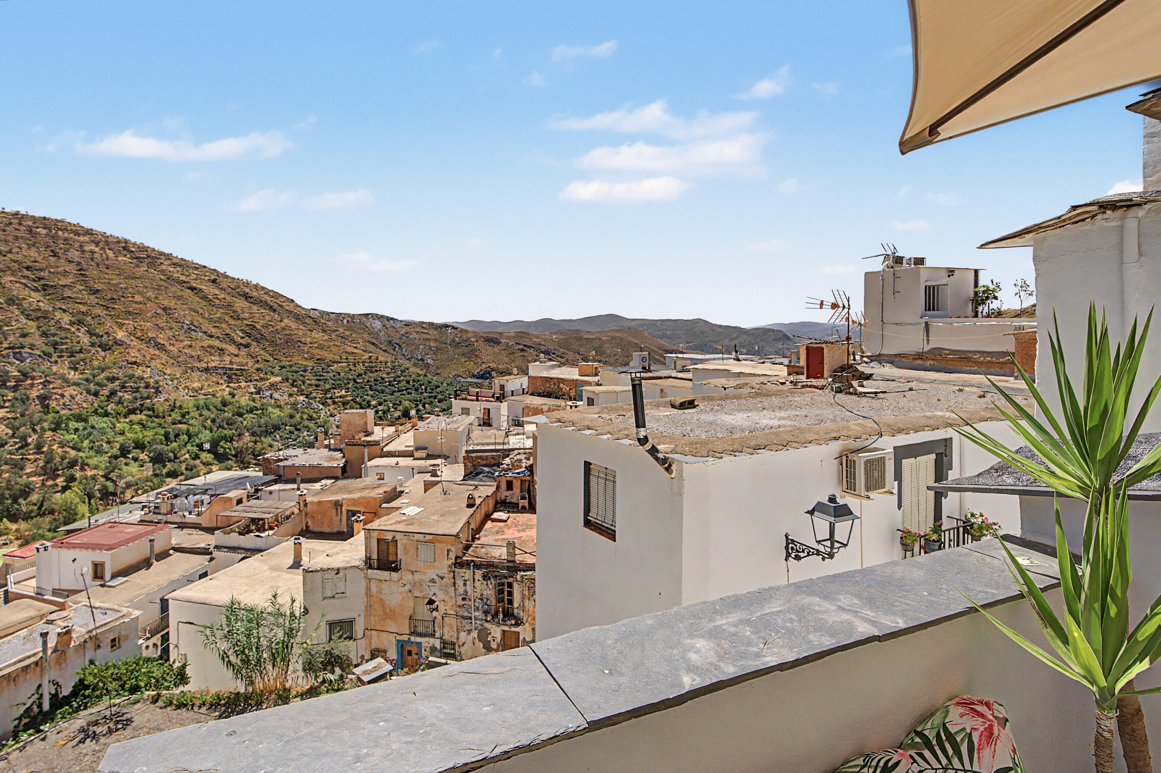 Zona residencial con casas adosadas, una colina al fondo y cielo despejado.