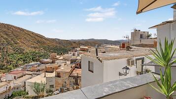 Zona residencial con casas adosadas, una colina al fondo y cielo despejado.