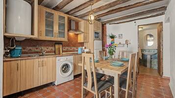 Une cuisine compacte avec des meubles en bois, un lave-linge et un coin repas avec une table dressée pour quatre personnes.