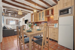 A cozy kitchen with wooden cabinets, a dining table set for four, and a modern microwave.