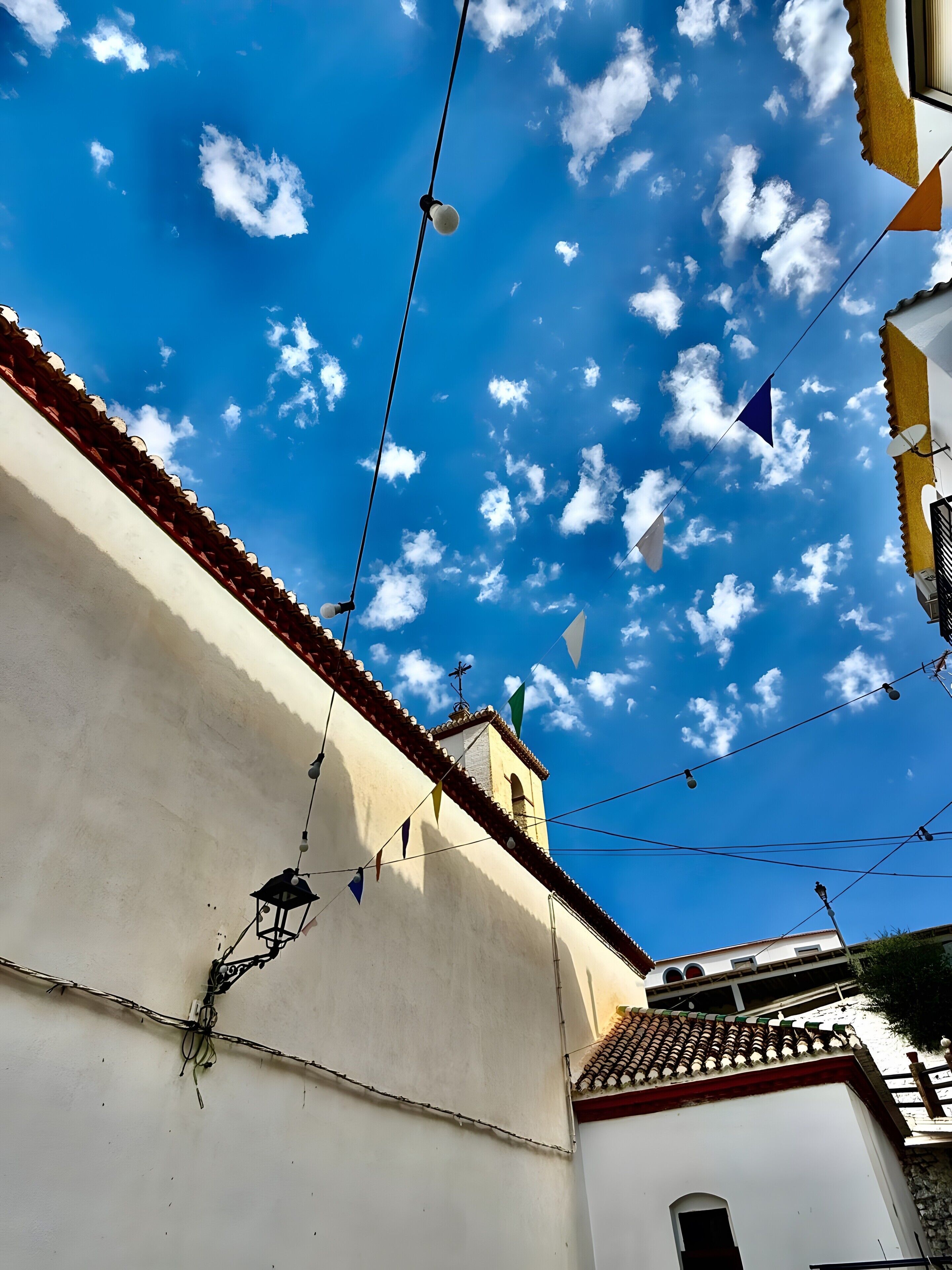 Ein Gebäude mit weißer Fassade und rotem Ziegeldach, vor einem wolkenlosen, blauen Himmel.