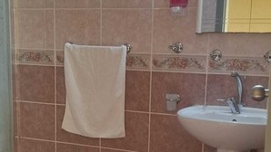 A bathroom with a sink, a towel hanging on the wall, and a mirror above the sink.