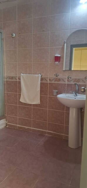 A bathroom with a sink, a towel hanging on the wall, and a mirror above the sink. - BARIŞ AİLE OTELİ (Silifke)