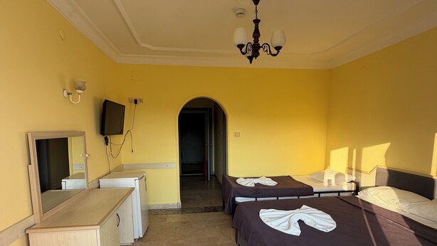 A hotel room with two beds, a desk, a wardrobe, and a television. - Baris Aile Oteli (Silifke)