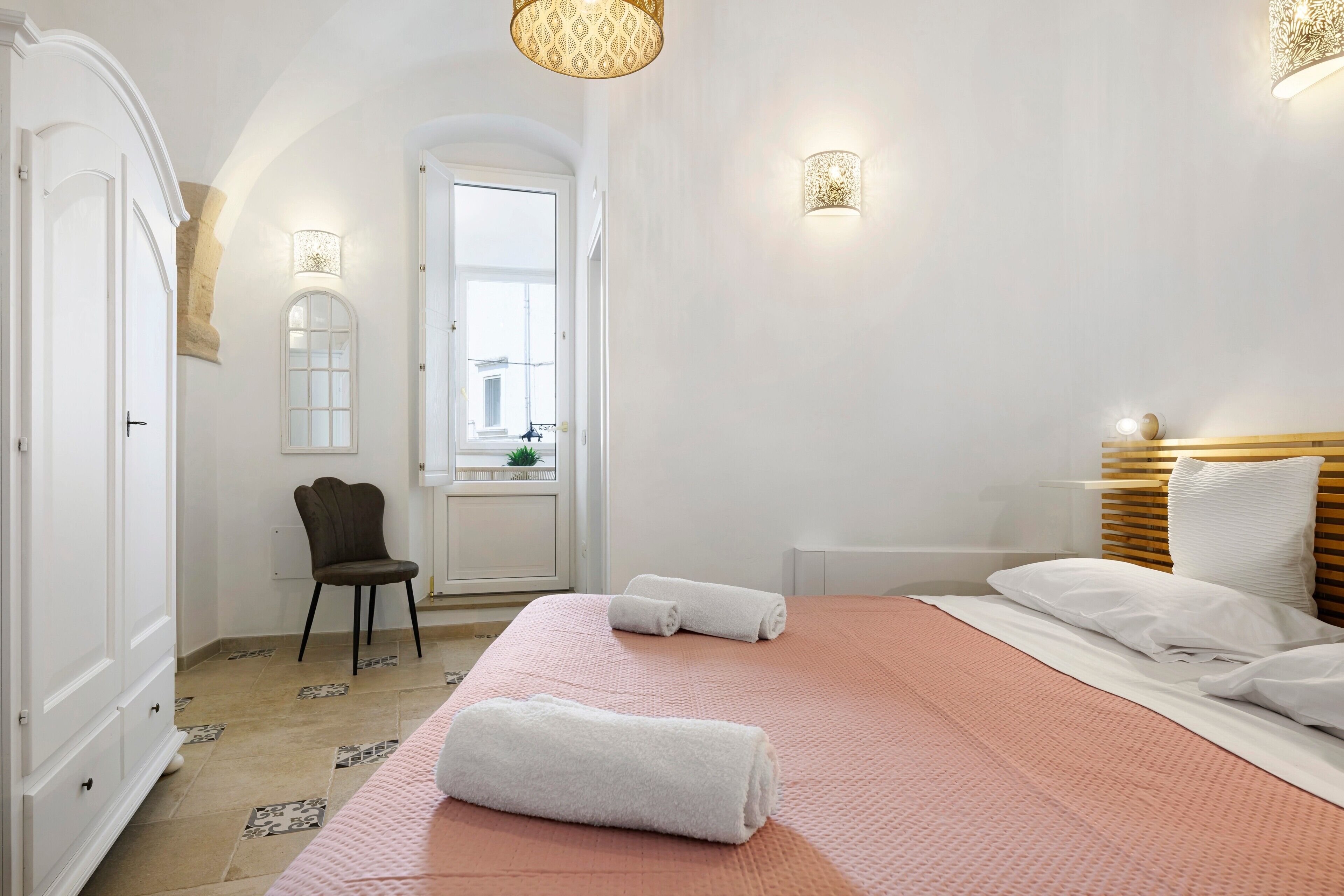 Een hotelkamer met een bed, een stoel, een bureau en een raam.