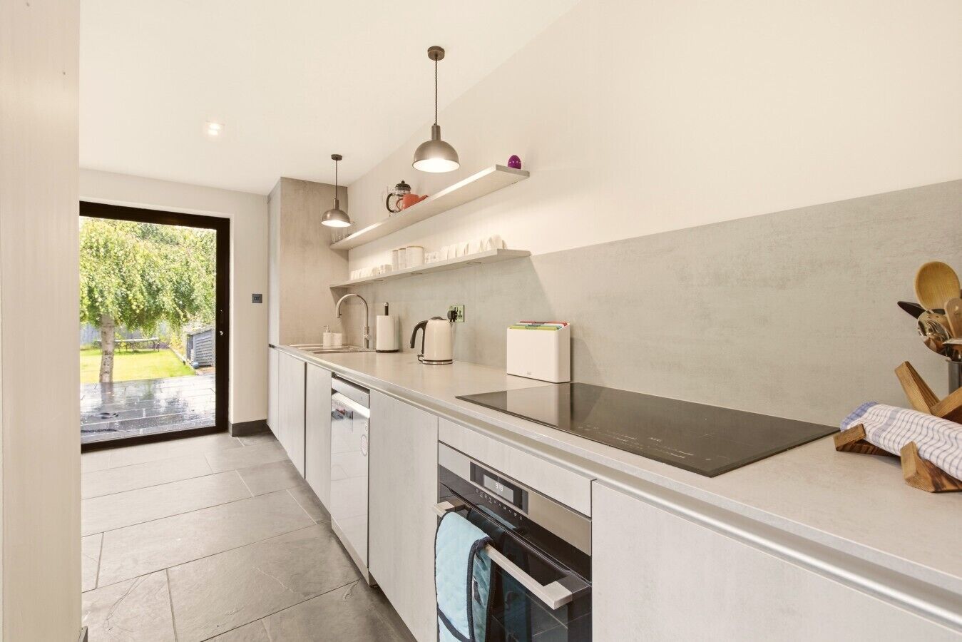 Bright galley kitchen with integrated appliances and garden views.