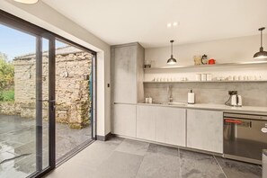 Contemporary kitchen with bi-fold doors opening onto the garden. - The Old Forge - North East Escapes (Warkworth)