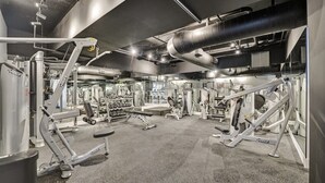 A gym with various exercise machines, a weight rack, and a large ventilation duct. - Bay & Ocean View 4 BDR Spacious Condo Resort Amenities 1616 (Miami Beach)