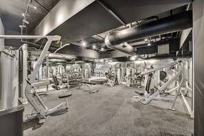 A gym with various exercise machines, a weight rack, and a large ventilation duct. - Bay & Ocean View 4 BDR Spacious Condo Resort Amenities 1616 (Miami Beach)