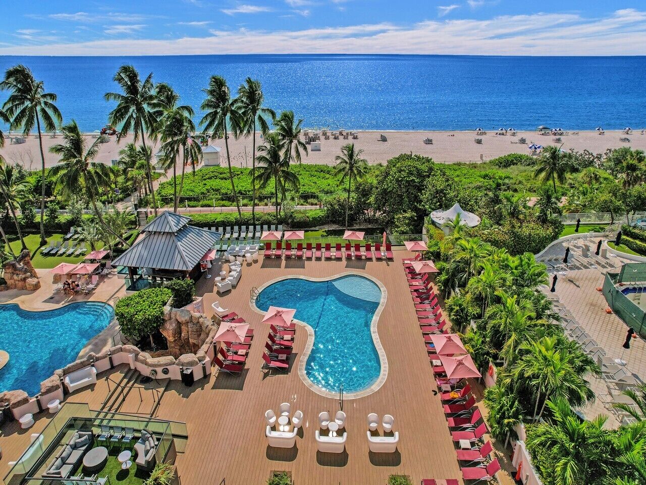 A resort with a large pool, lounge chairs, and a beach view.