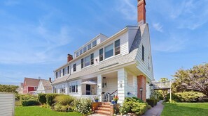 A two-story house with a porch, a chimney, and a well-maintained lawn. - Walk to the Beach From This East End Retreat (Provincetown)